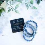 The Evoline Blue Kyanite Energetic alignment and clear communication bracelet shown with meaning card and stacked bracelet style. 