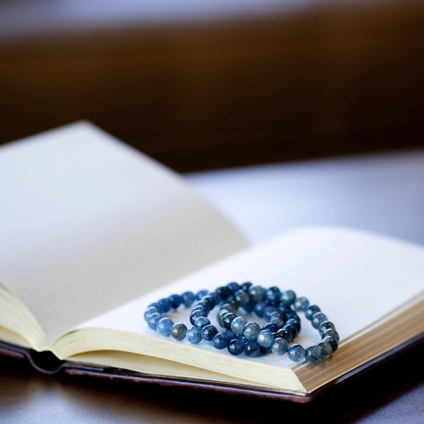 The Evoline Blue Kyanite bracelet shown in a stacked style on a mediation book. 