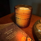 The Align Candle in a textured glass holder with a ritual card on a wooden surface.