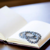 The Evoline Labradorite bracelet shown in a stacked style on a meditation book.