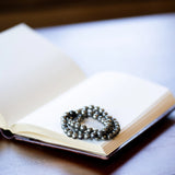 The Evoline Pyrite Abundance & Security Bracelets stacked on a meditation book.