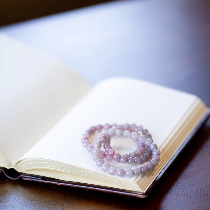 The Evoline Rose Quartz Unconditional Love Bracelets on a mediation book.