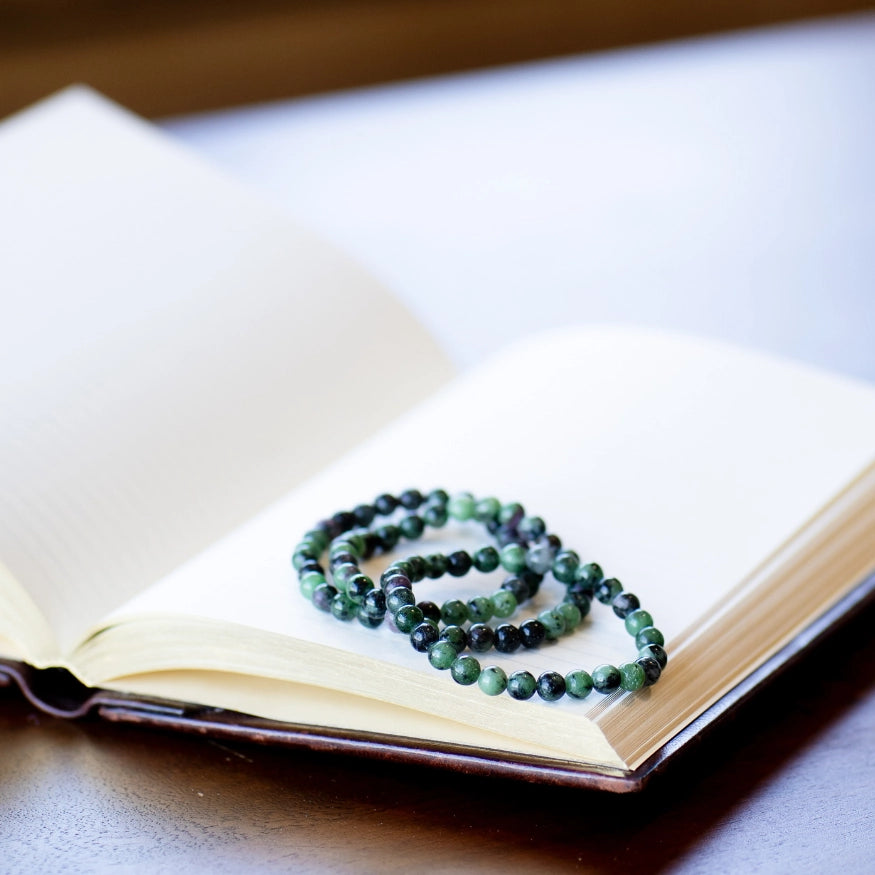The Evoline Ruby & Zoisite Aligned growth and soul healing Bracelets stacked on a meditation book.