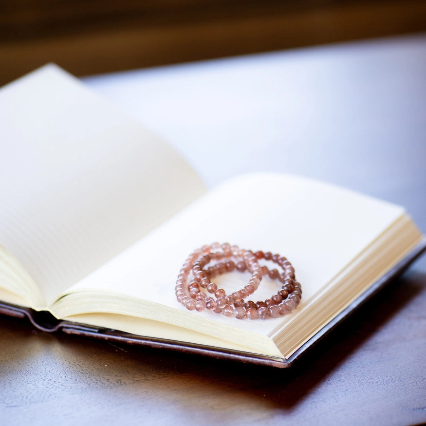 The Evoline Sunstone Empowerment & Leadership Bracelets stacked on mediation book.