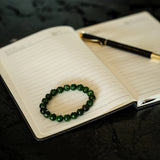 Diopside Green beaded bracelet on an open notebook with a pen