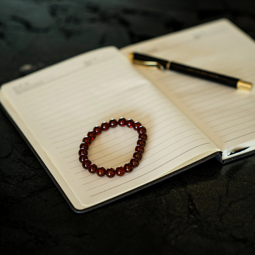 Orange Garnet Bracelet on a notebook with a pen on a dark surface
